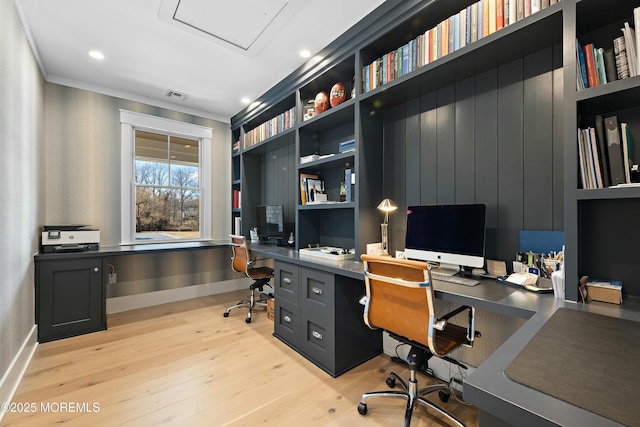 office area featuring built in shelves, light wood-style flooring, visible vents, ornamental molding, and built in desk