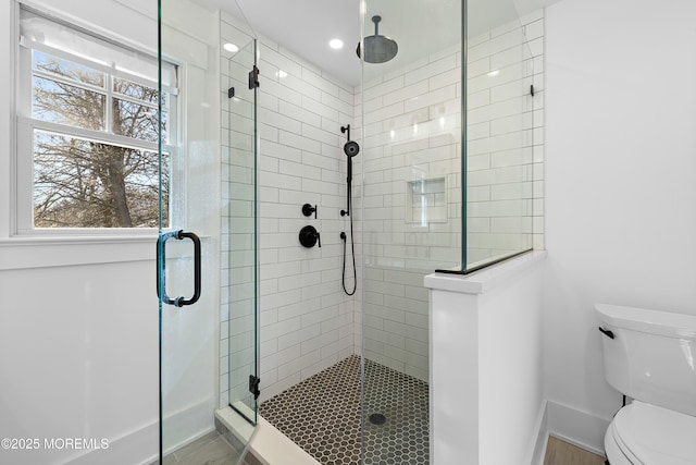 bathroom with a stall shower, toilet, and baseboards