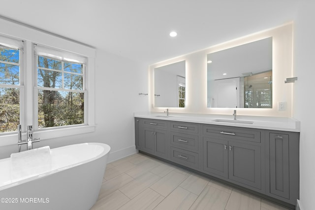 bathroom featuring a stall shower, a healthy amount of sunlight, a sink, and double vanity