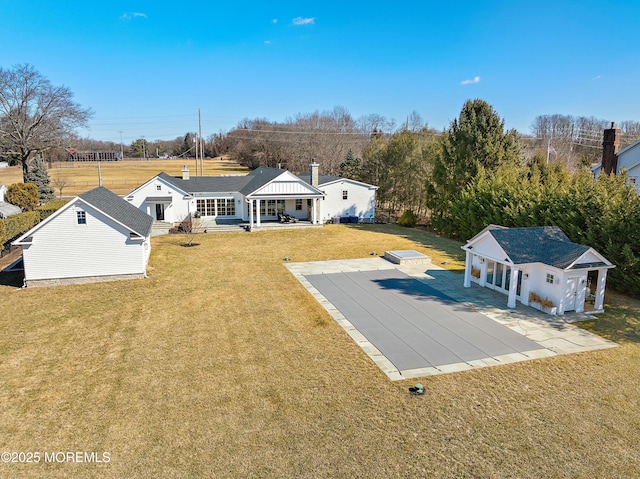 back of property featuring an outbuilding, covered porch, a lawn, and concrete driveway