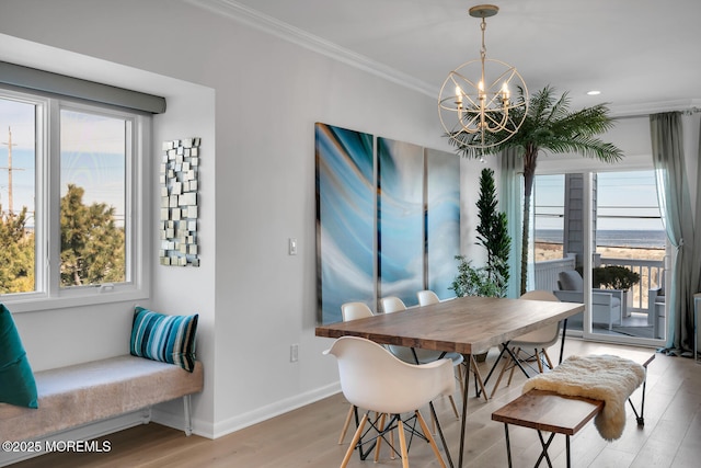 dining area featuring ornamental molding, a healthy amount of sunlight, a notable chandelier, and light wood-style flooring