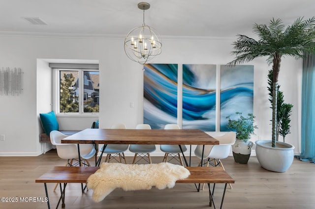 dining space with ornamental molding, light wood-type flooring, a chandelier, and visible vents