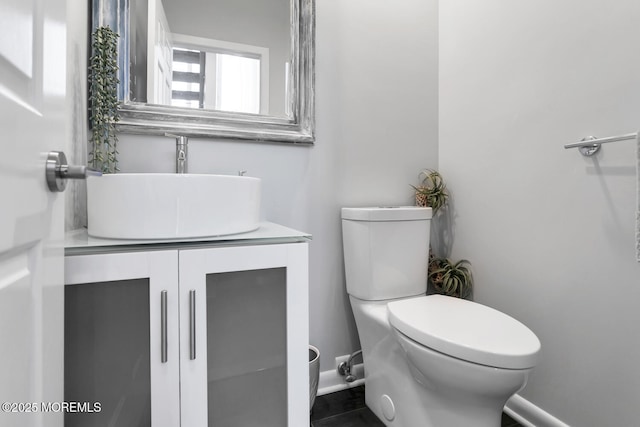 bathroom with baseboards, vanity, and toilet