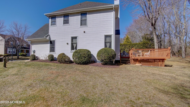 back of house with a wooden deck, a chimney, a shingled roof, and a yard