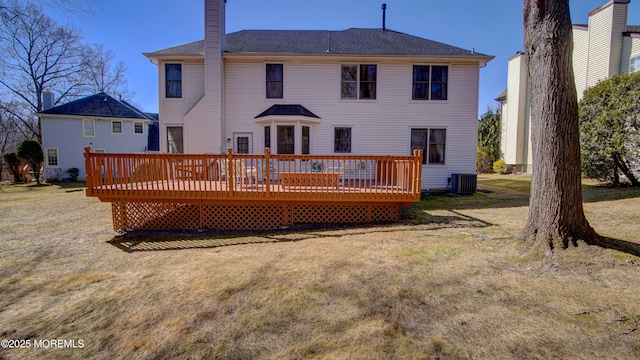 back of house featuring a chimney, central AC unit, a lawn, and a wooden deck