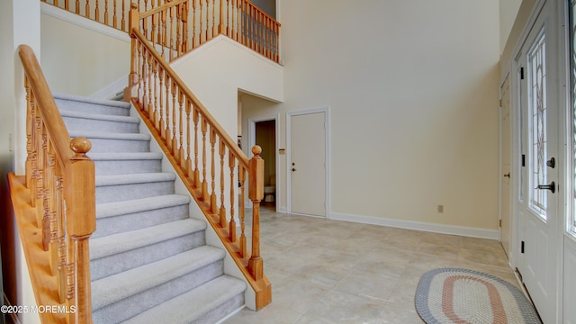 entrance foyer featuring stairway, a high ceiling, and baseboards