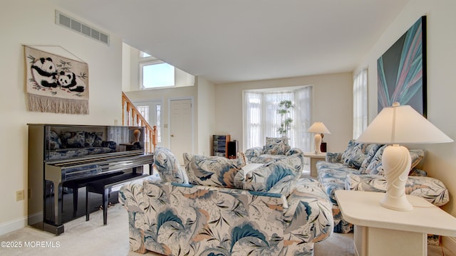 living room featuring light colored carpet, visible vents, baseboards, and stairs