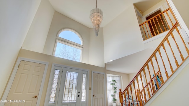 foyer featuring stairway, a towering ceiling, and a notable chandelier