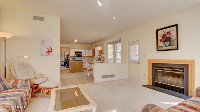 living room featuring a fireplace with flush hearth, visible vents, and light colored carpet