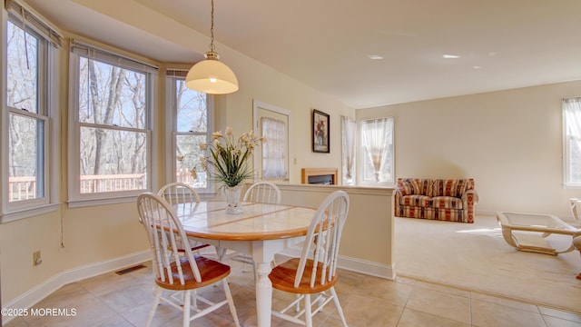 dining space with visible vents, plenty of natural light, light carpet, and light tile patterned flooring