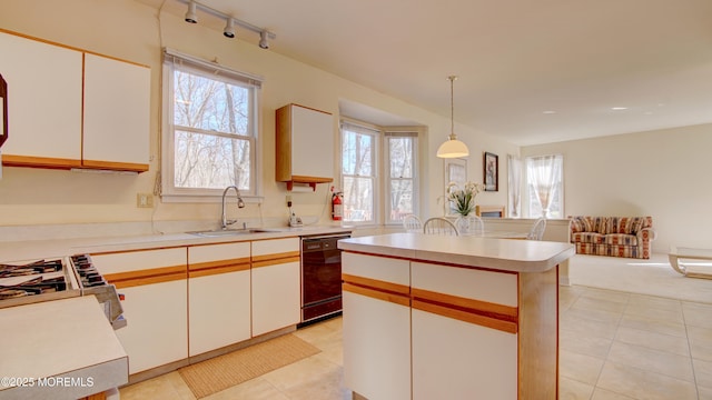 kitchen with white cabinets, dishwasher, light countertops, pendant lighting, and a sink