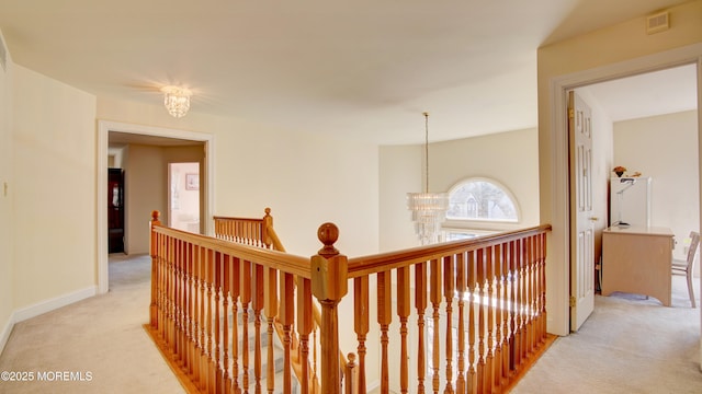 corridor featuring light carpet, visible vents, a chandelier, and an upstairs landing