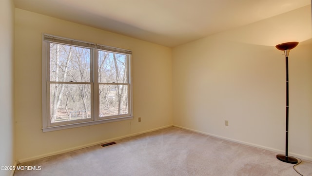 empty room featuring carpet, visible vents, and baseboards