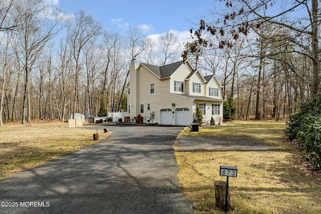 view of home's exterior with aphalt driveway, an attached garage, and a yard