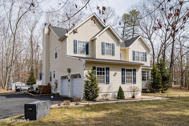 traditional-style house featuring a front lawn, a garage, driveway, and a chimney