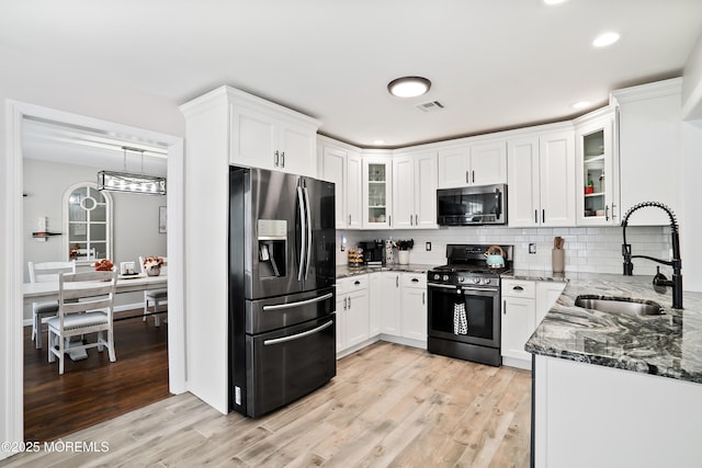 kitchen with dark stone countertops, visible vents, a sink, appliances with stainless steel finishes, and white cabinetry