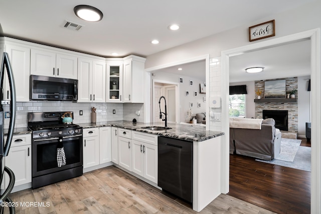 kitchen with visible vents, dark stone countertops, a sink, white cabinetry, and stainless steel appliances