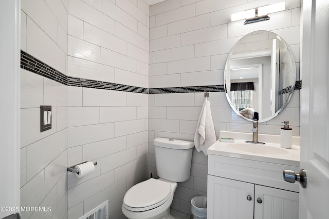 half bathroom featuring toilet, tile walls, and vanity