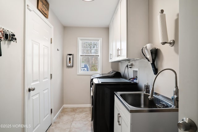 clothes washing area with baseboards, light tile patterned floors, washer and dryer, cabinet space, and a sink