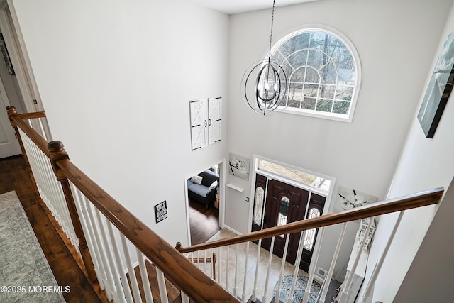 stairway featuring a notable chandelier and wood finished floors