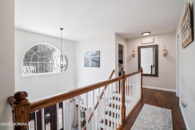 corridor with a chandelier, an upstairs landing, baseboards, and wood finished floors