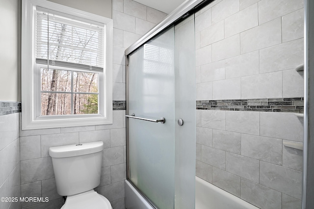 full bathroom featuring tile walls, toilet, and bath / shower combo with glass door