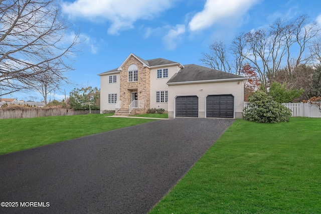 view of front of property featuring an attached garage, fence, aphalt driveway, and a front yard