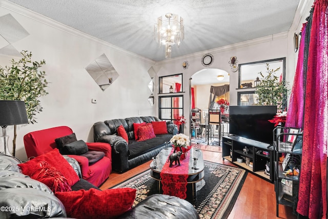 living room featuring arched walkways, ornamental molding, a textured ceiling, and wood finished floors