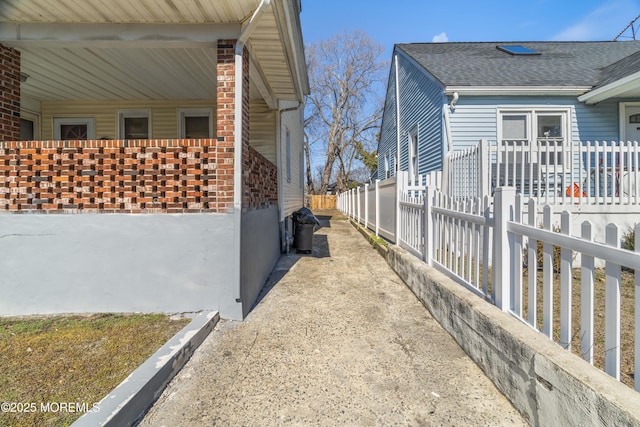 view of side of home featuring fence and roof with shingles