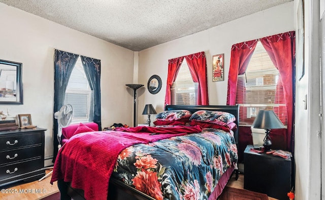 bedroom with a textured ceiling, baseboard heating, and wood finished floors