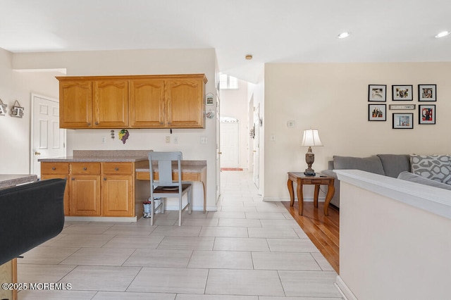 kitchen featuring baseboards, brown cabinets, open floor plan, light countertops, and recessed lighting