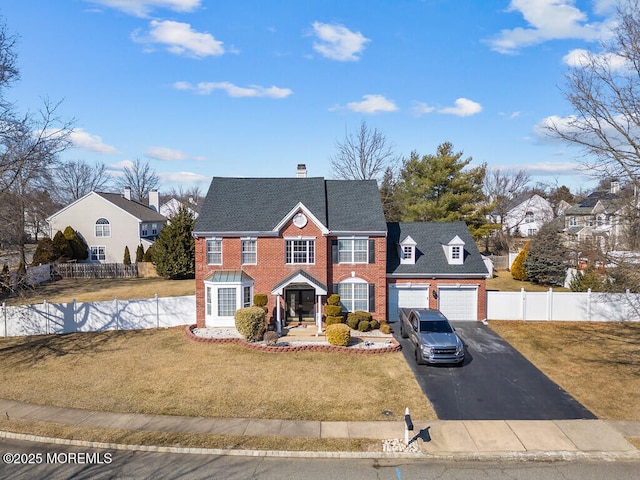 view of front of home with brick siding, an attached garage, a front yard, fence, and driveway