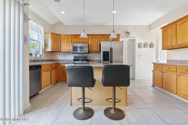 kitchen with a kitchen island, a breakfast bar area, stainless steel appliances, light countertops, and a sink