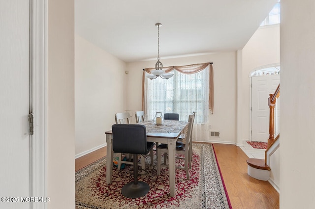 dining space featuring stairs, wood finished floors, visible vents, and baseboards