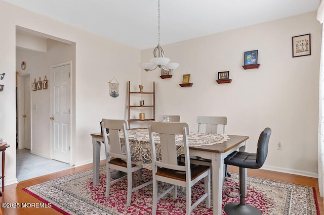 dining space with baseboards, an inviting chandelier, and wood finished floors