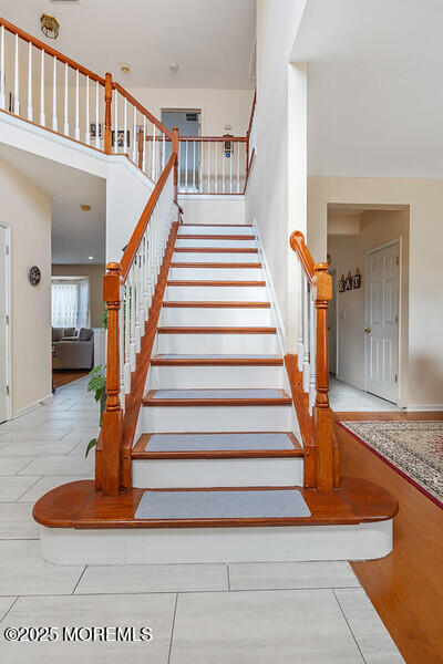 stairway with a high ceiling and wood finished floors