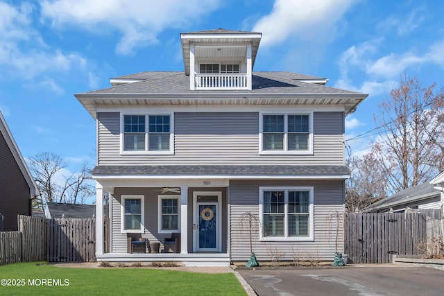 american foursquare style home with covered porch, roof with shingles, and fence