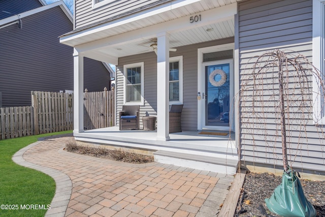 property entrance featuring covered porch and fence