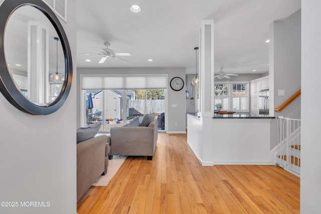 living area featuring light wood-style floors, a wealth of natural light, recessed lighting, and stairs