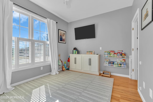 playroom with ceiling fan, light wood-style flooring, and baseboards