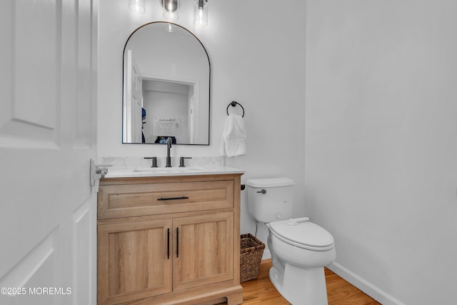 bathroom featuring baseboards, vanity, toilet, and wood finished floors