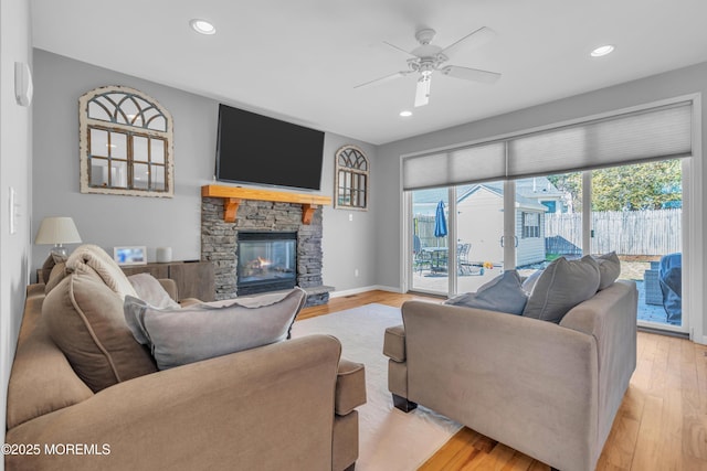 living area with a fireplace, recessed lighting, light wood-style flooring, a ceiling fan, and baseboards