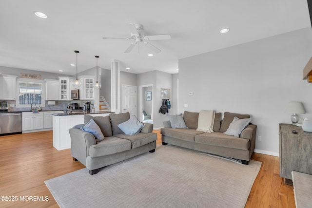 living room with baseboards, a ceiling fan, light wood-style flooring, stairs, and recessed lighting