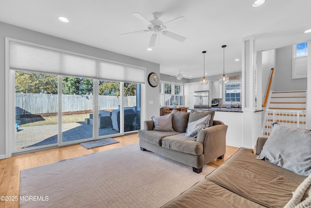 living room with a ceiling fan, recessed lighting, light wood-style flooring, and stairs