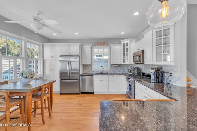 kitchen featuring stainless steel appliances, tasteful backsplash, white cabinetry, a sink, and light wood-type flooring