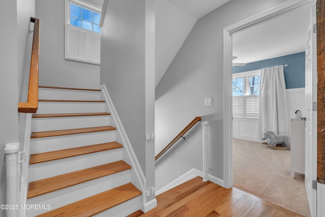 staircase with carpet floors, baseboards, and wood finished floors