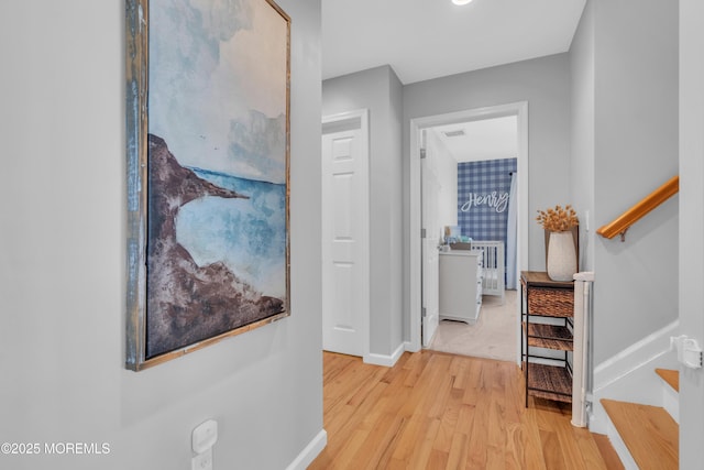 corridor featuring light wood finished floors, visible vents, stairs, and baseboards