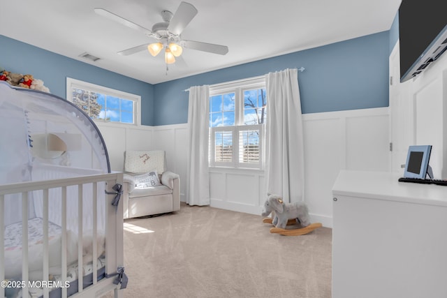 bedroom featuring multiple windows, visible vents, carpet flooring, and wainscoting