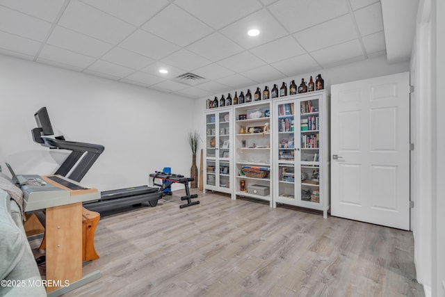 workout area featuring a paneled ceiling, visible vents, wood finished floors, and recessed lighting