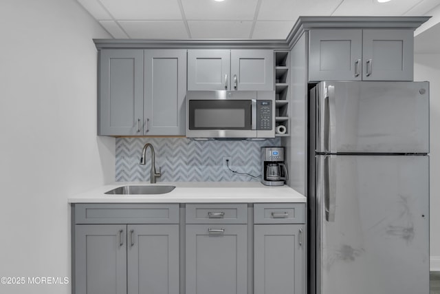 kitchen with backsplash, stainless steel appliances, gray cabinets, and a sink